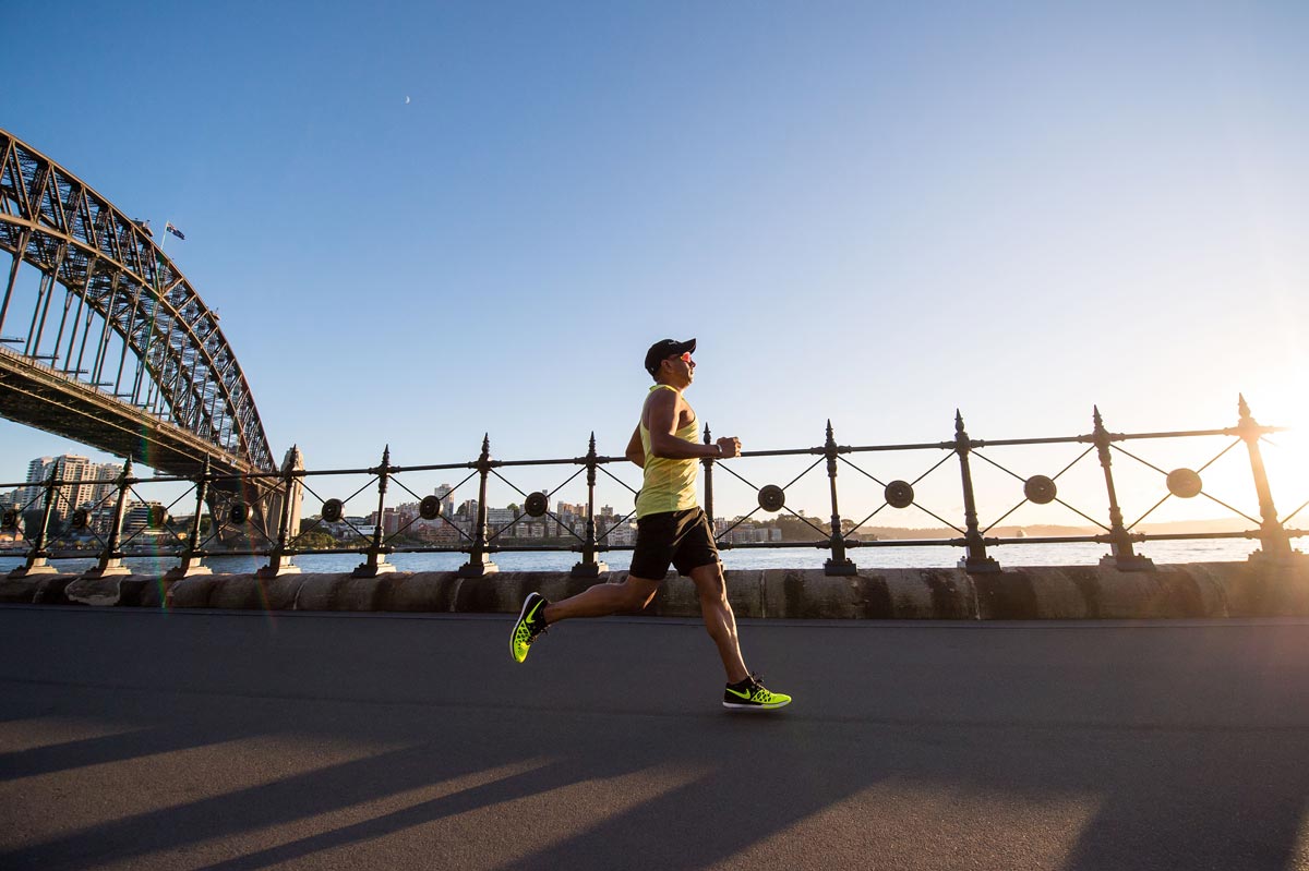 Man in yellow shirt running at sunrise.